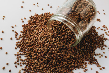 Raw buckwheat in glass on white background, heathy food, diet