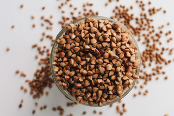 Raw buckwheat in glass on white background, heathy food, diet