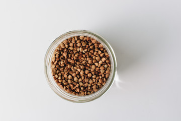 Raw buckwheat in glass on white background, heathy food, diet