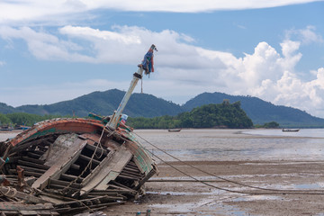 Abandoned wrecked fishing boat by the sea on a cloudy day. Scenic sea-side landscape.