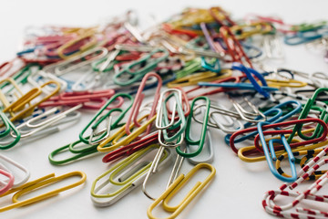 Pile of colorful paper clips on white background, flat lay