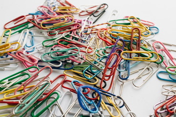 Pile of colorful paper clips on white background, flat lay