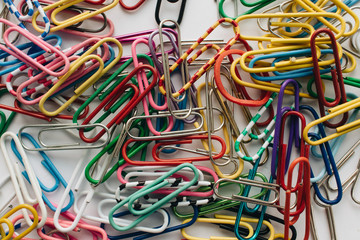 Pile of colorful paper clips on white background, flat lay