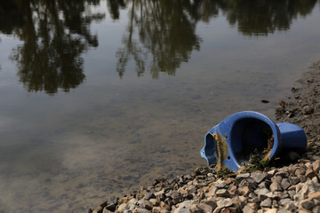 Dump thrown into the river. Toilet bowl lying down on river shore. Ecological problems