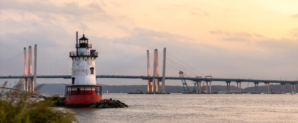 Panorama of a caisson (sparkplug) style lighthouse under soft golden light with a bridge in the background. Tarrytown Light on the Hudson River in New York. 