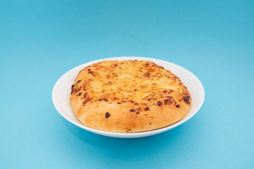 Fresh round cake on white plate on blue background.
