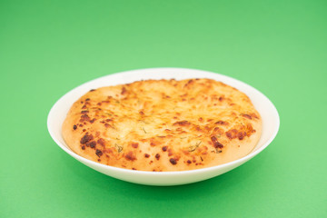 Fresh round cake on white plate on green background.