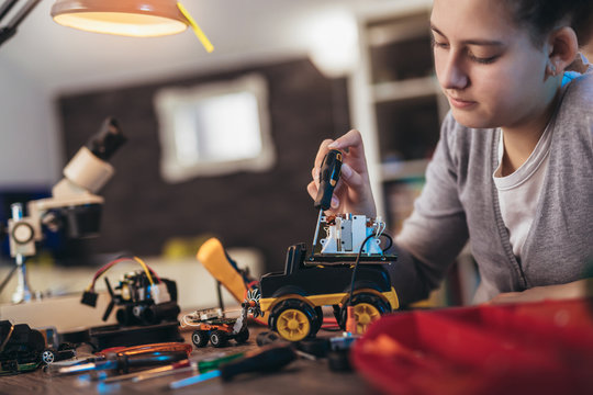 Girl constructs technical toy. Technical toy on table full of details