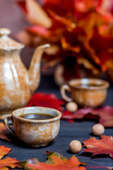 Morning coffee in mugs and coffee pot on a dark wooden background with maple leaves