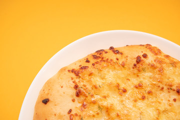 Fresh round cake on white plate on yellow background.