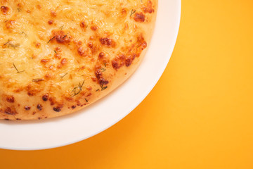 Fresh round cake on white plate on yellow background.