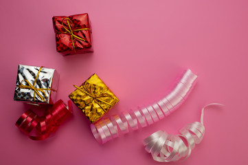 Gift Boxes Silver, Golden, Red and Decorative Ribbons Lie on a Pink Background.