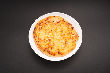 Fresh round cake on white plate on black background.