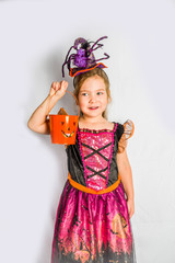 Little cute girl in witch costume for Halloween with jack-o-lantern bucket for Halloween trick or treating. White wall background copy space