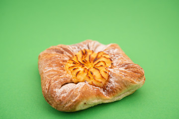 Fresh bun of unusual shape on green background.