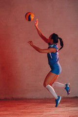 Young Asian woman volleyball player in blue uniform innings ball
