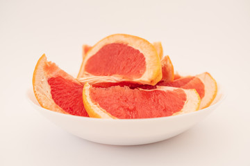 Naklejka na ściany i meble Fresh ripe juicy grapefruit on white plate on white background.