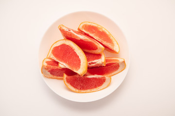 Fototapeta na wymiar Fresh ripe juicy grapefruit on white plate on white background.