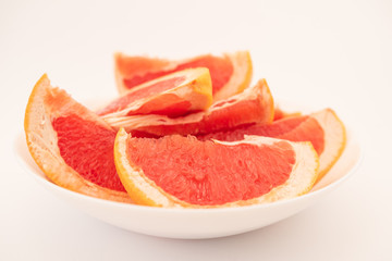 Naklejka na ściany i meble Fresh ripe juicy grapefruit on white plate on white background.
