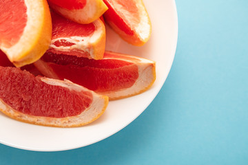 Fototapeta na wymiar Fresh ripe juicy grapefruit on white plate on blue background.