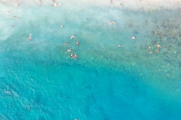 An aerial shot of people enjoying the summer at the beach at daytime 