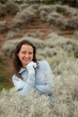 Portrait of attractive woman wearing blue gloves and sweater. Pretty Caucasian woman smiling and touching her chin. Christmas and New Year holidays.