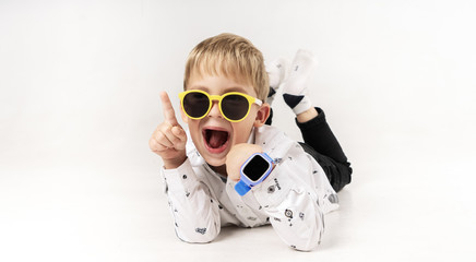 A little boy in yellow sunglasses and blue children's smart watches. © Aboltin