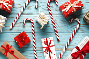 Fototapeta premium Flat lay composition of christmas gift boxes and candy canes on a blue wooden background