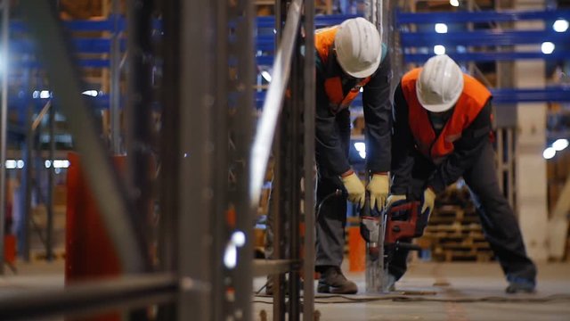 workers in helmets fix rack carcass in warehouse slow motion