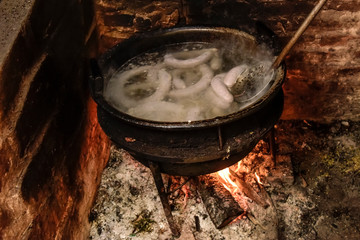 Cooking white blood sausage, in an iron saucepan, on a stove.