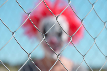 scary clown behind a fence