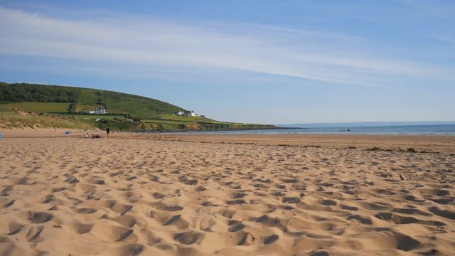 Low angle static shot from the sea and the sandy beach, during sunset and blue sky in Croyde, UK.