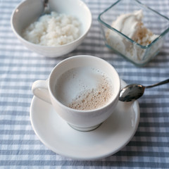 White cup of coffee with milk and rice porridge 