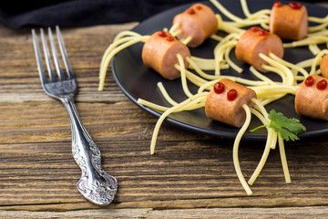 spaghetti with sausages in the form of spiders. Happy kid food for Halloween party.