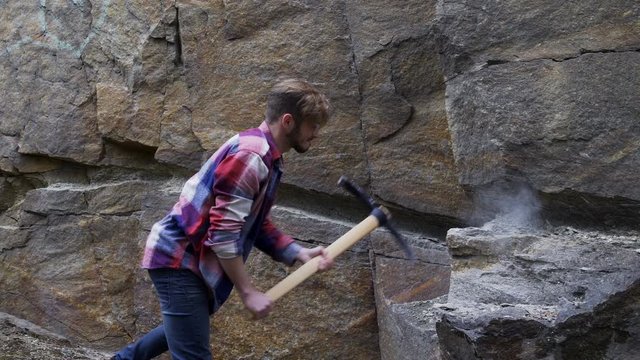 Man mining stone with a pickaxe. Not very effective tool and very hard work. Could be used as an abstract shot of bad job or wrong tools, inefficient workflow.