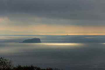 Skrypleva Island, where Vladivostok's oldest lighthouse is located, lit by the sun breaking through thunderclouds.
