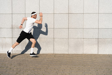 Fototapeta premium Handsome man running in the city. Fitness, workout, sport, lifestyle concept.