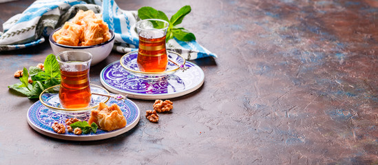 Traditional Turkish arabic dessert and a glass of tea with mint
