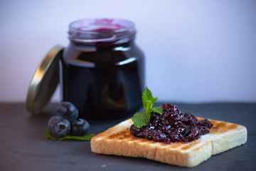 Spread toasted blueberry jam with mint on blackboard with white background