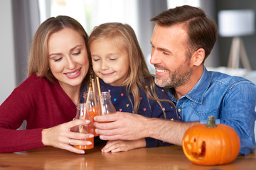 Family with pumpkin smoothie making a toast to halloween