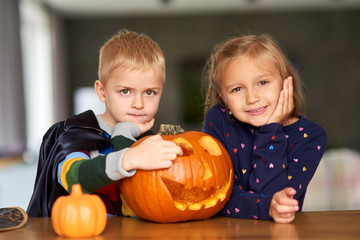 Fototapeta premium Portrait of charming little boy and girl with halloween pumpkin