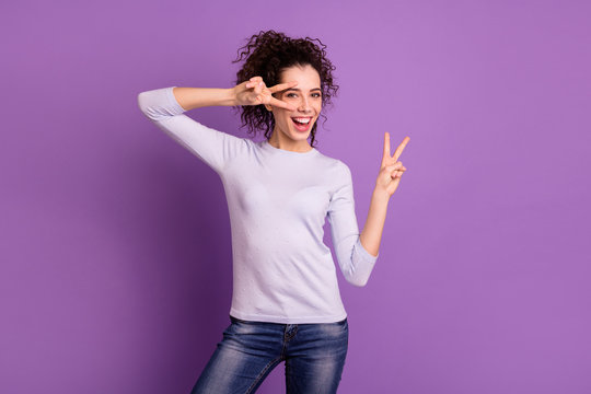 Photo of amazing wavy lady with beaming toothy smile holding hands in v-sign symbols near eyes positive mood wear pullover isolated purple color background