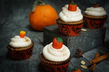 Homemade pumpkin Cupcakes with cream cheese frosting with halloween candy topping, selective focus