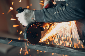 Craftsman sawing metal with disk grinder saw in workshop