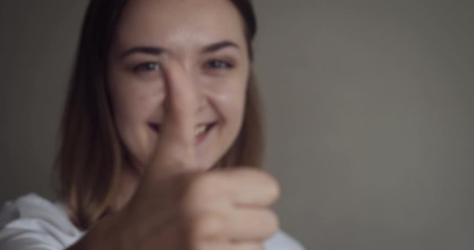 Young woman shows thumbs up sign.