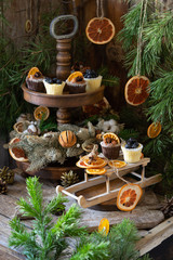 Christmas cupcakes made of white and dark chocolate, decorated with berries, nuts and slices of tangerines. Christmas decor in Scandinavian style. A wonderful composition for a Christmas card