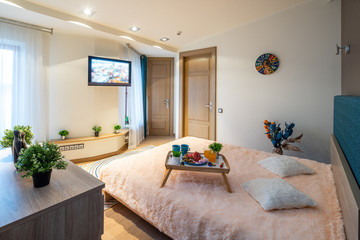 Interior of bedroom. Modern apartment. King-size bed. Tray with food.