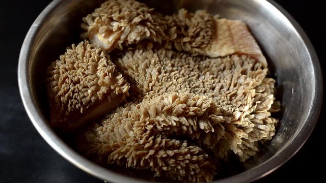 Sliced pieces of raw beef stomach are collected in a bowl and poured with water. Preparatory stage for further preparation.