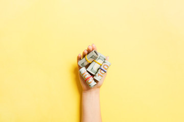 Top view of rolled up in tubes dollar bills in female palm on colorful background. Poverty and debt concept