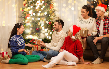 celebration and holidays concept - happy friends with glasses celebrating christmas at home party and giving presents